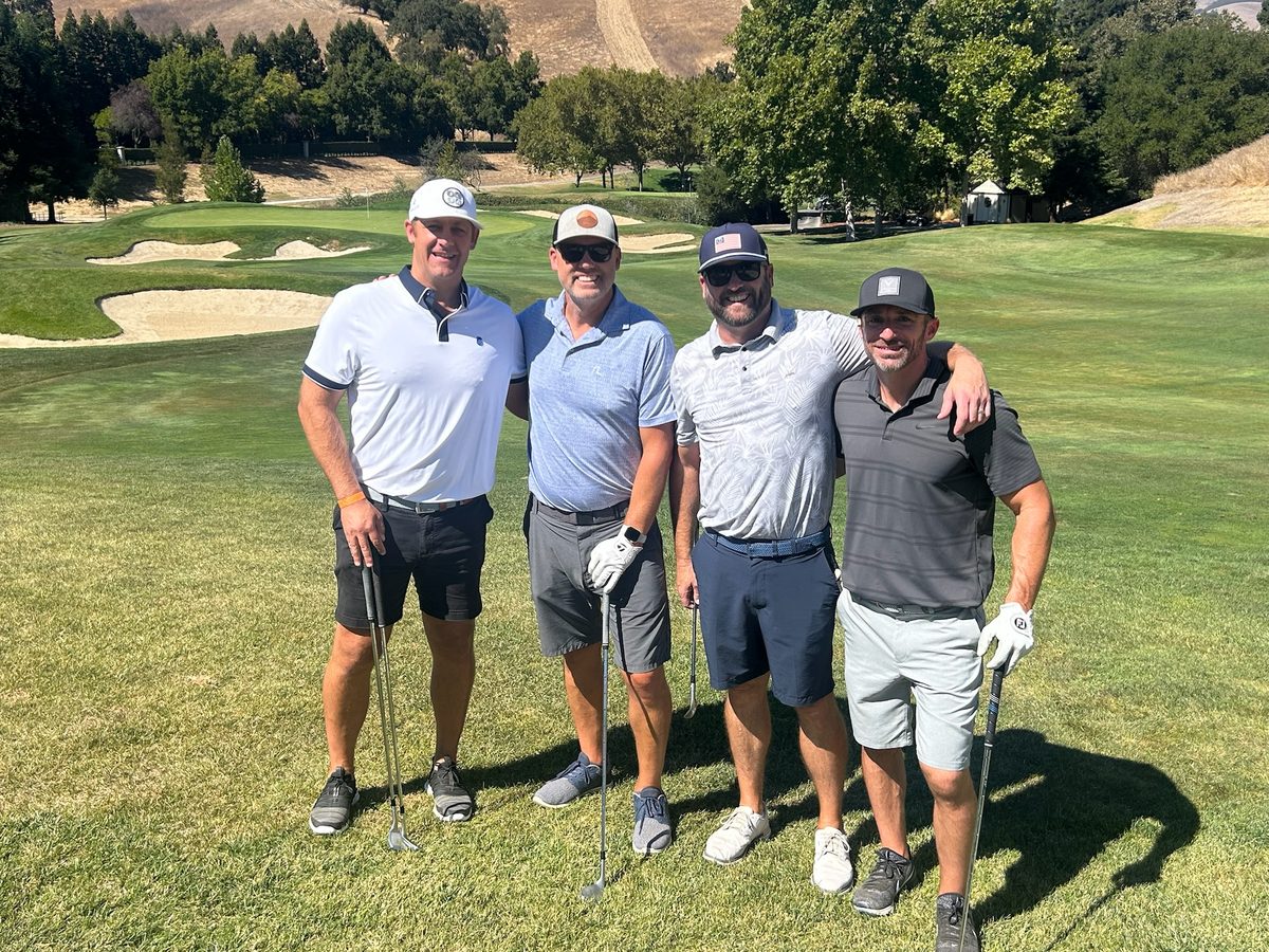 Foursome posing on the green at the SIS Golf Classic