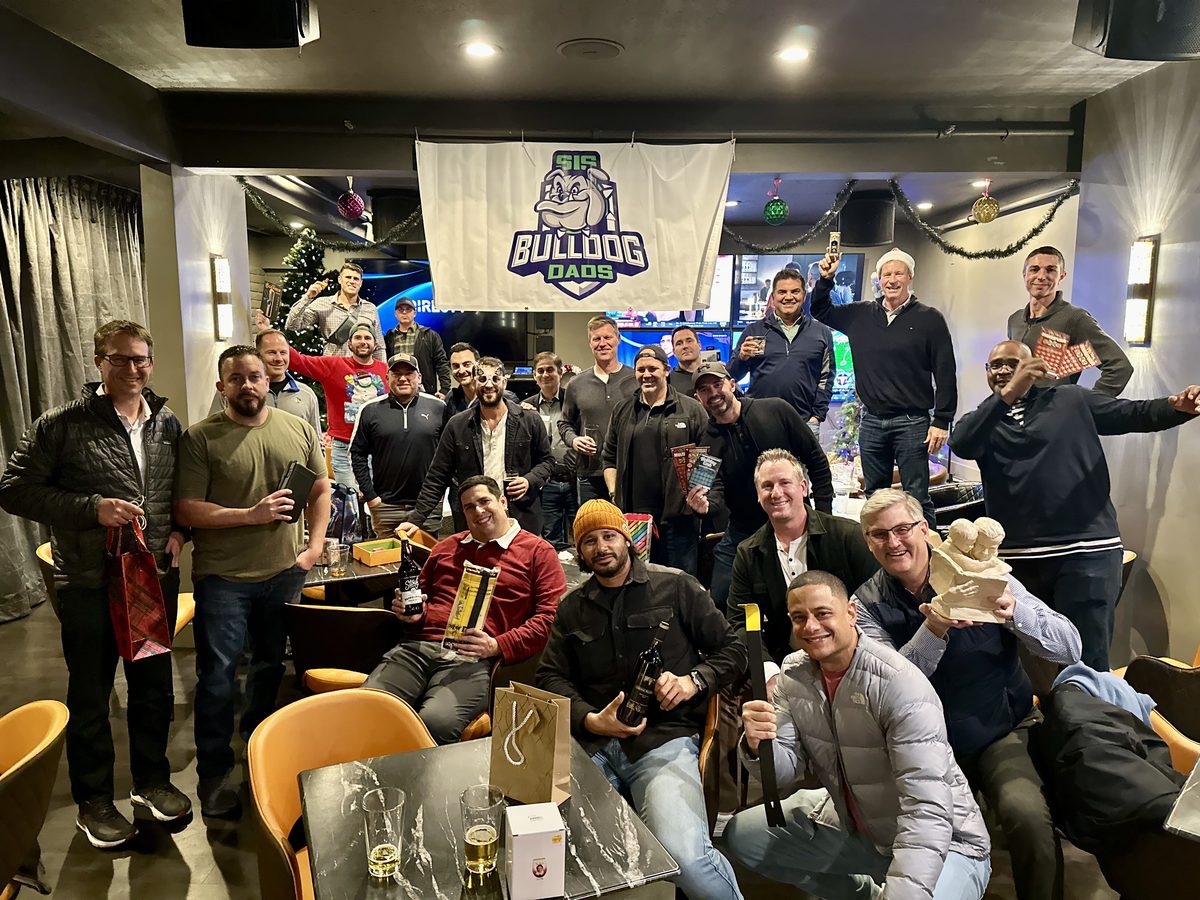 Group of dads at a sports bar with Bulldog Dads banner