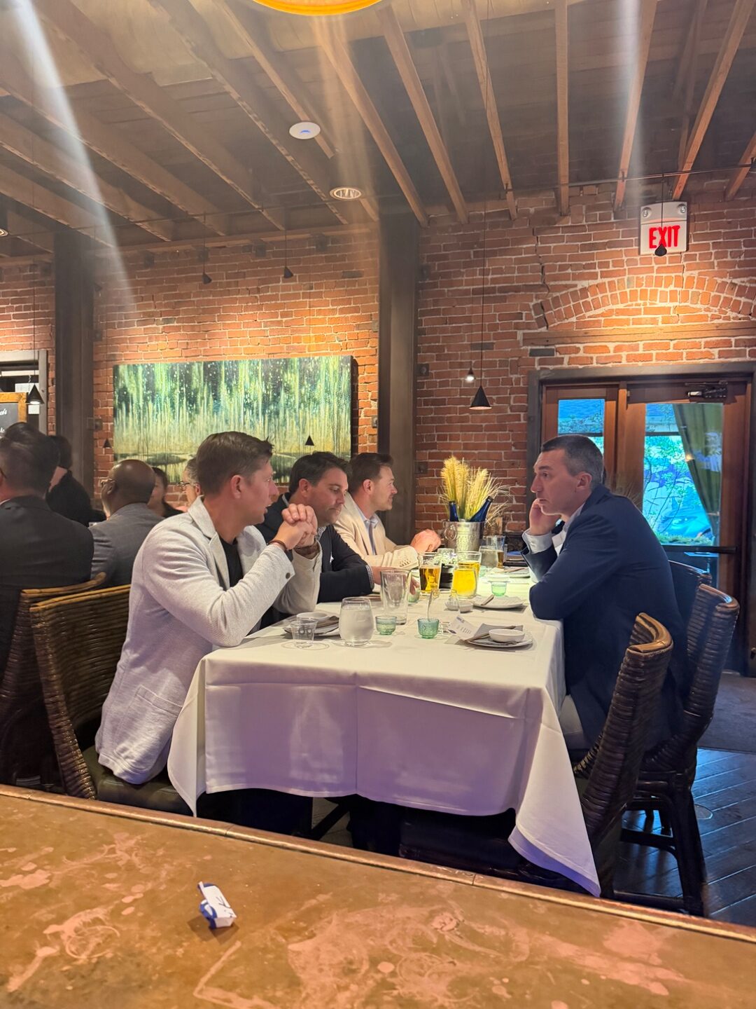 Long communal dinner table set with dinner jacket attendees raising glasses