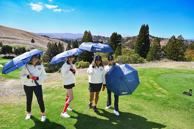 Foursome with BNY umbrellas on the tee, 2026 SIS Golf Classic