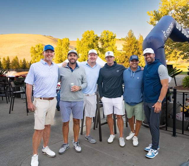 Foursome at golden hour on the patio, 2026 SIS Golf Classic